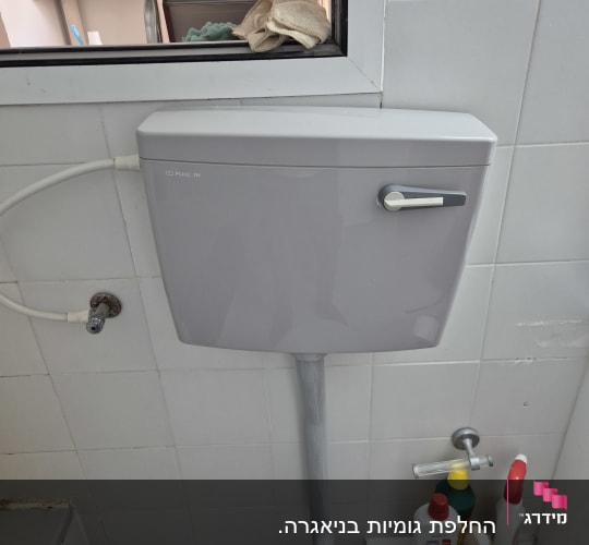 אסלה עם מיכל הדחה ומוצרי ניקוי בחדר אמבטיה